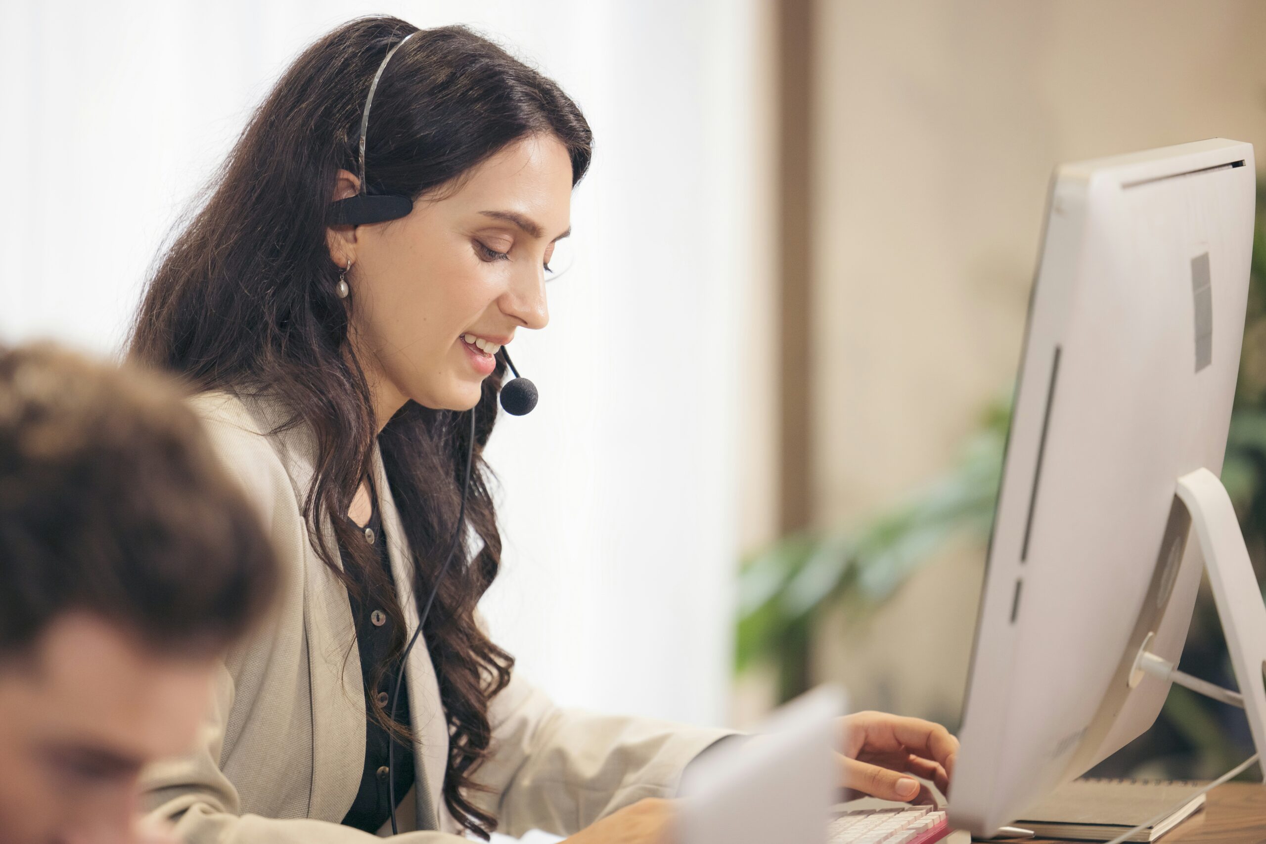 Professional woman wearing a headset and smiling while providing outsourced HR services